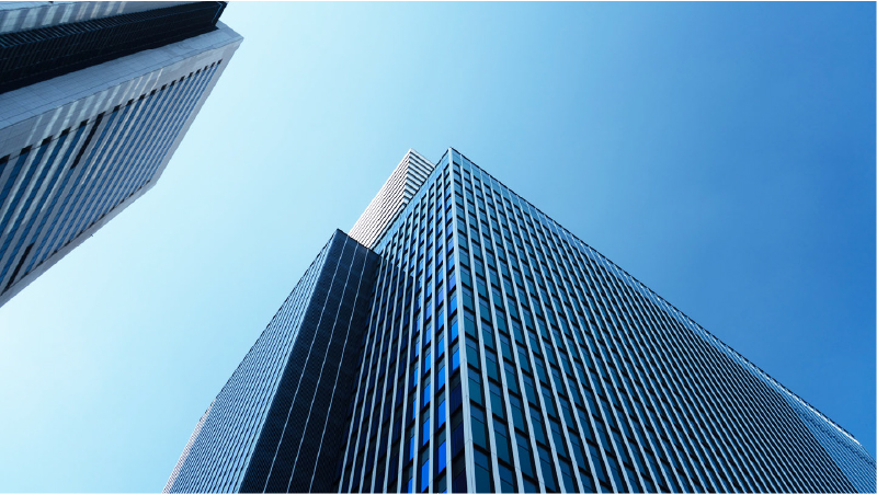 青空を背景に見上げた高層ビルの外観を写した会社イメージ写真