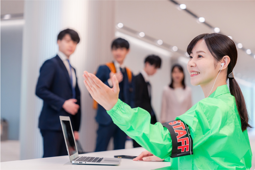 イベント会場で来場者に説明を行いながら接客対応をするスタッフの様子