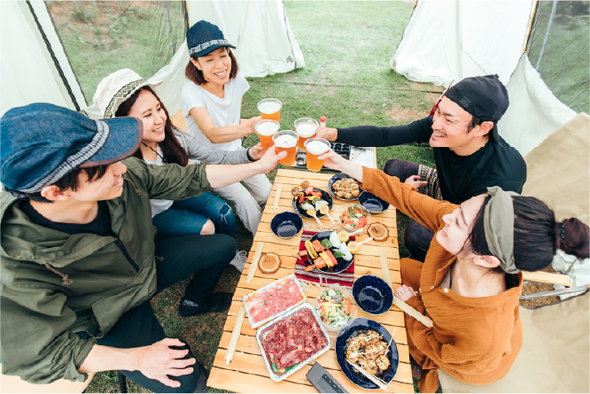 バーベキュー交流会で食事を囲みながら笑顔で談笑する社員の様子、社内表彰式で登壇者のプレゼンテーションを聞く社員の様子、懇親会で乾杯しながら和やかに交流する社員の様子、打ち上げの席でグラスを手に会話を楽しむ社員の様子